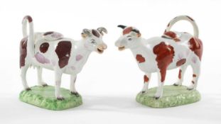 TWO SWANSEA PEARLWARE COW CREAMERS, both pink lustre and red spotted decoration, on grassy plinth