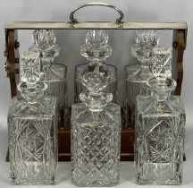 20TH CENTURY SILVER PLATED & MAHOGANY THREE-BOTTLE TANTALUS & THREE FURTHER CUT GLASS DECANTERS, the