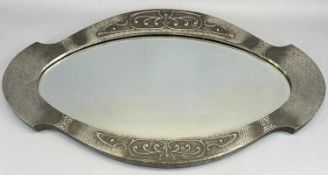 ARTS & CRAFTS HAMMERED PEWTER FRAMED WALL MIRROR, of shaped oval design and embossed with stylised