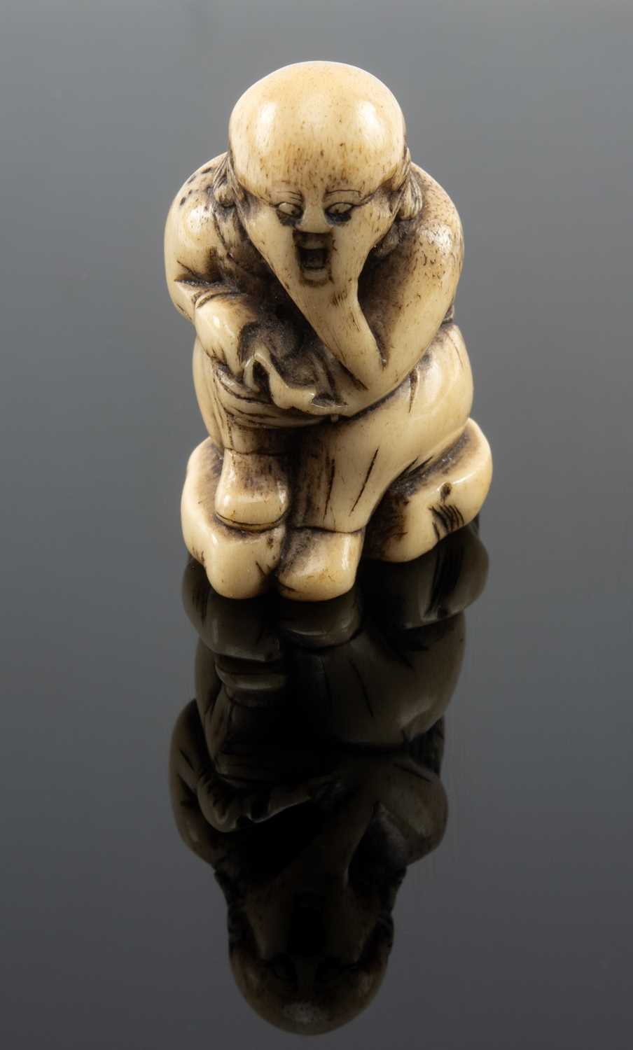 JAPANESE STAG ANTLER NETSUKE, Edo Period, stained and carved as a seated Sage holding his knee,