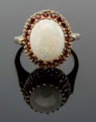 9CT GOLD OPAL & GARNET HALO RING, the large central oval opal with border of tiny garnets, ring size