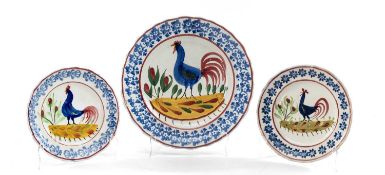THREE VARIOUS LLANELLY POTTERY COCKEREL PLATES circa 1900, typical sponged borders in blue, the