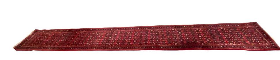 EASTERN RED GROUND WOOLEN RUNNER with repeating central pattern, and triple bordered edge, 500 x