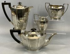 GEORGE V SILVER FOUR-PIECE TEA SERVICE of oval panelled form, teapot and hot water pot with ebonised
