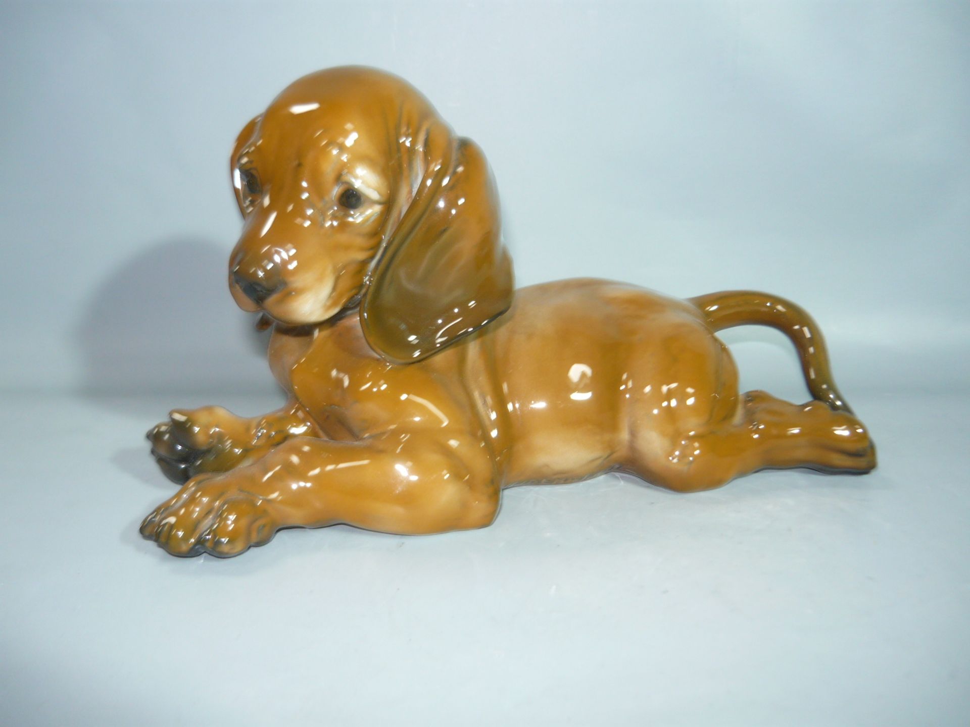 Rosenthal. Liegender Dackel. H. 21cm. //English: Rosenthal. Lying Dachshound. First choice.