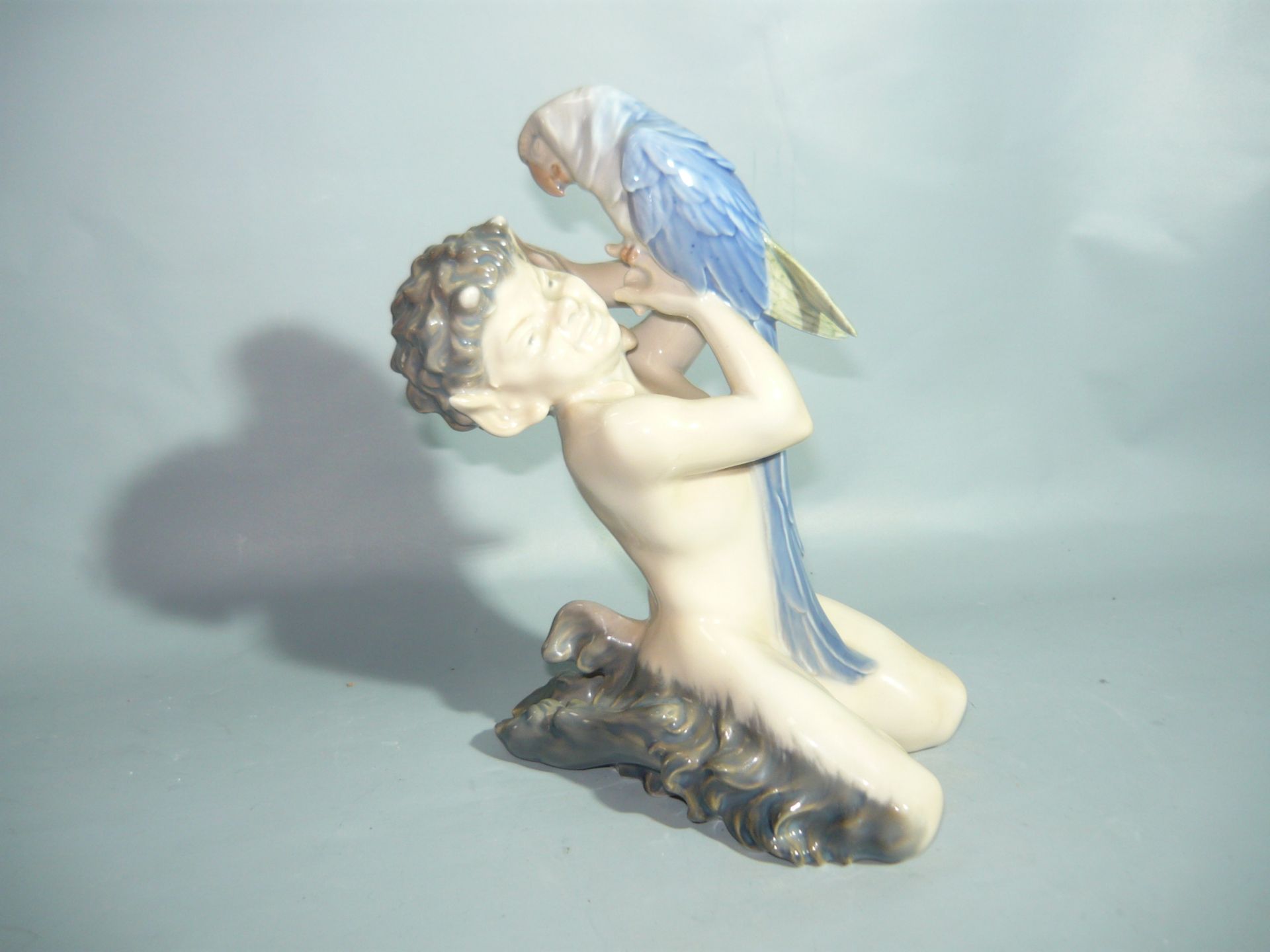 Royal Copenhagen. Sitzender Faun mit blauem Ara. Erste Wahl. H. 19cm. //English: Royal Copenhagen.