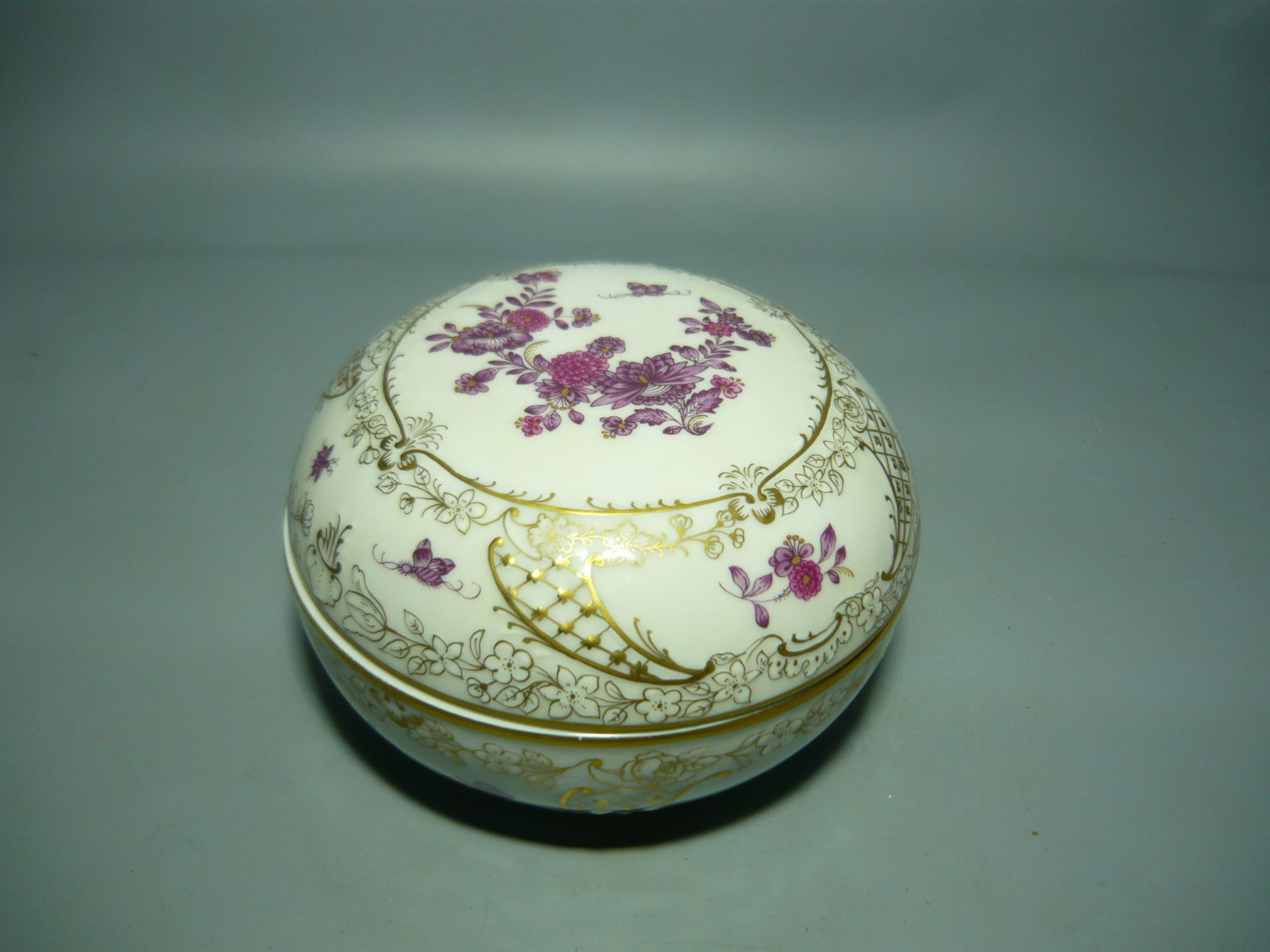 Meissen (Schwerter). Prunkvolle Deckeldose mit reicher Bemalung. Deputat mit Hausmalerei. Ca. 13x9cm