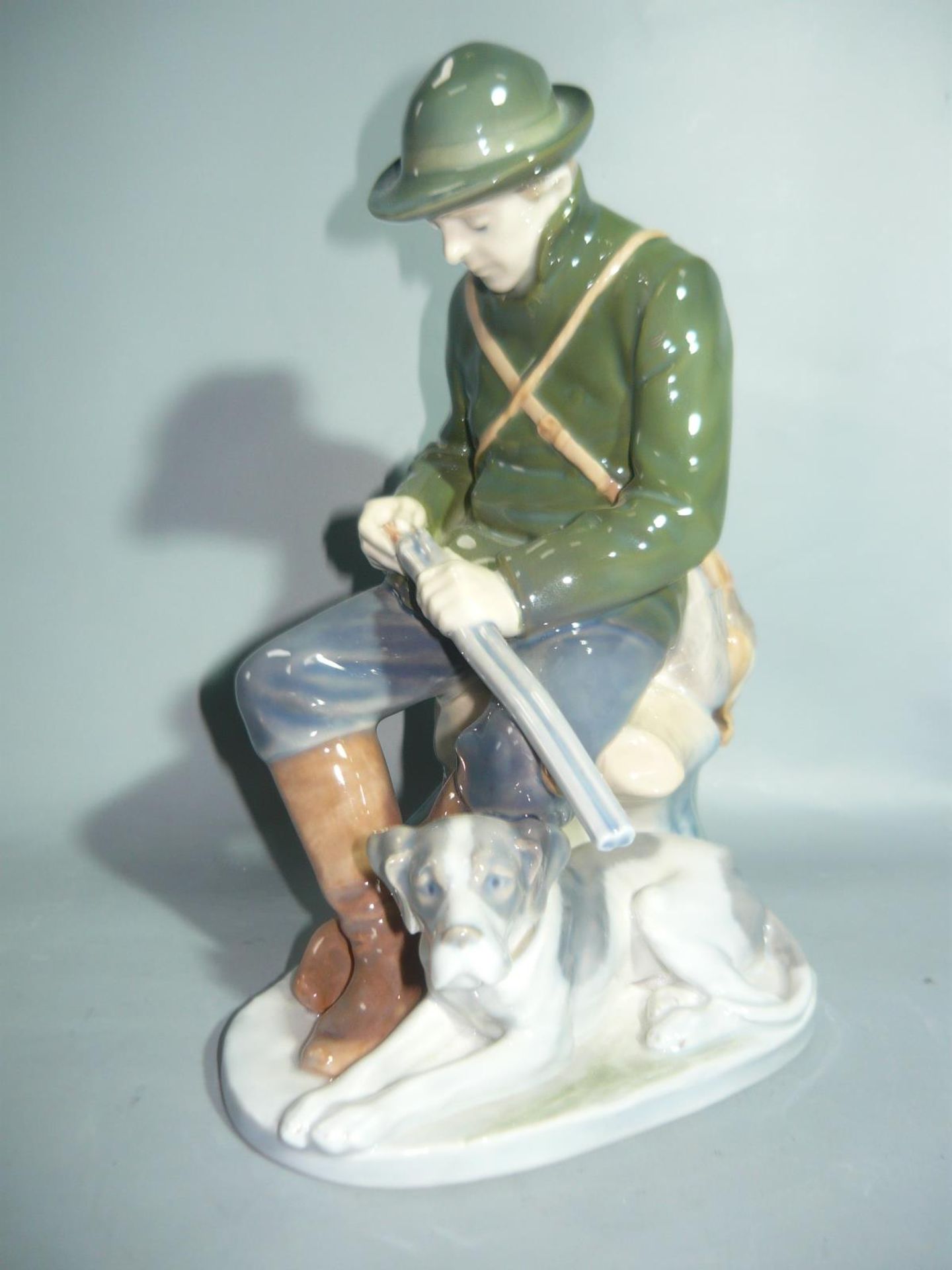 Royal Copenhagen. Jäger mit Jagdhund. II.W. H. 22cm. //English: Royal Copenhagen. Huntsman with dog.