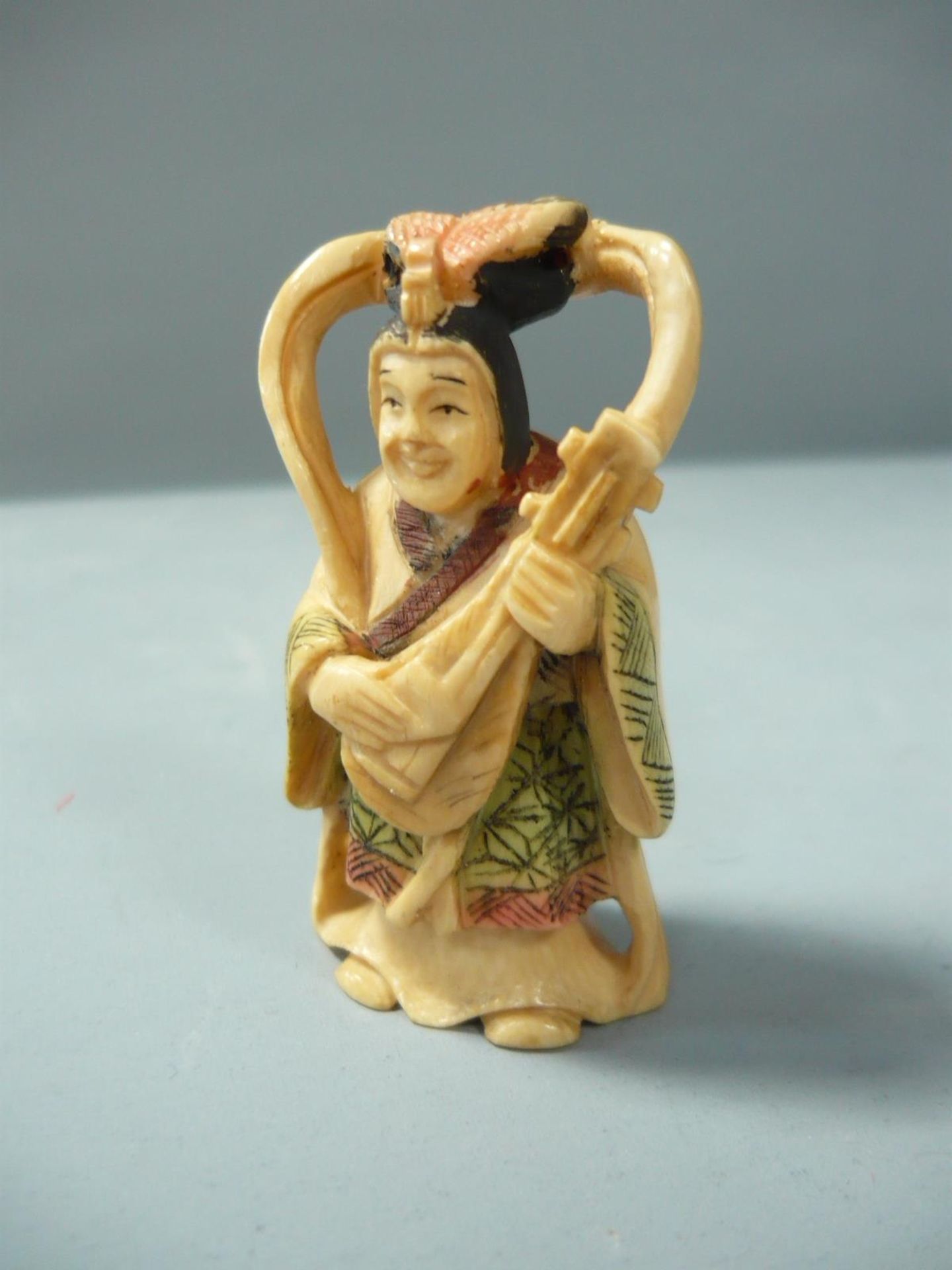 Netsuke. Musikantin. Bein, geschnitzt. Asien 20.jhdt. Im Boden Signiert. H. 6 cm. // English: