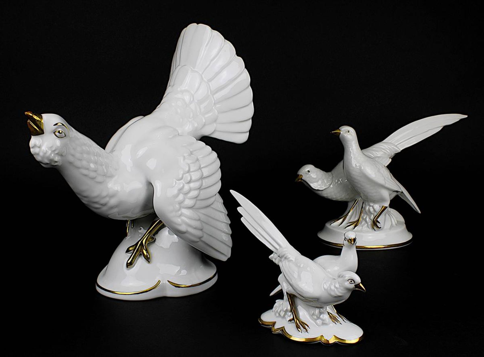 Drei Vogelfiguren bzw. Figurengruppen, deutsch M. 20. Jh., Weißporzellan mit Goldstaffage: balzender