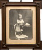 Fotografie "Kleines Mädchen auf dem Stuhl stehend mit Eimer in der Hand", um ca. 1900, schwarz/ wei