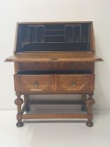 Arts & Crafts period oak fall-front, 2-drawer bureau measuring H:104 x W:76 x D:44. Collection only.