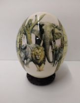 Ostrich egg on plinth, decorated with African animal scene to the front and world map on the