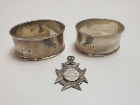 Hallmarked silver items including a pair of napkin rings and a sports fob. Shipping Group (A).