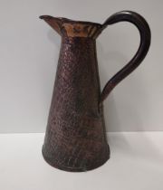 An Arts & Crafts period hammered copper jug. 34cm tall Shipping Group (A).
