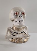 Cast metal money box in the form of a skeleton/skull, having pop-out eyes when coins inserted.