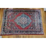 A red ground Persian village Rug from the Surok region with multi borders and central medallion