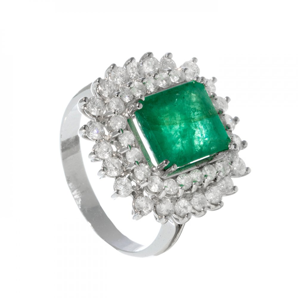 Ring in 18kt white gold. Model with central emerald of ca. 4.50 cts. and border of diamonds with ca.