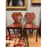 Late 19th/ Early 20th century A pair of mahogany hall chairs With carved detail to the backs