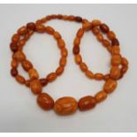 BUTTERSCOTCH AMBER BEADED NECKLACE (SMALL DAMAGE TO ONE BEAD) - 70 GRAMS APPROX