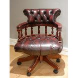 A captain's chair, mahogany frame with padded red wine leather upholstery, button backed, rotating