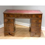 A mahogany knee pedestal desk, with wine red leatherette skiver, one drawer flanked by two smaller