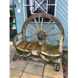 A rustic wooden two seater cartwheel garden seat. L120cm, H128cm, D53cm.