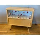 A 1950s kitchen cabinet, the upper section with two sliding glass doors above two louvered sliding