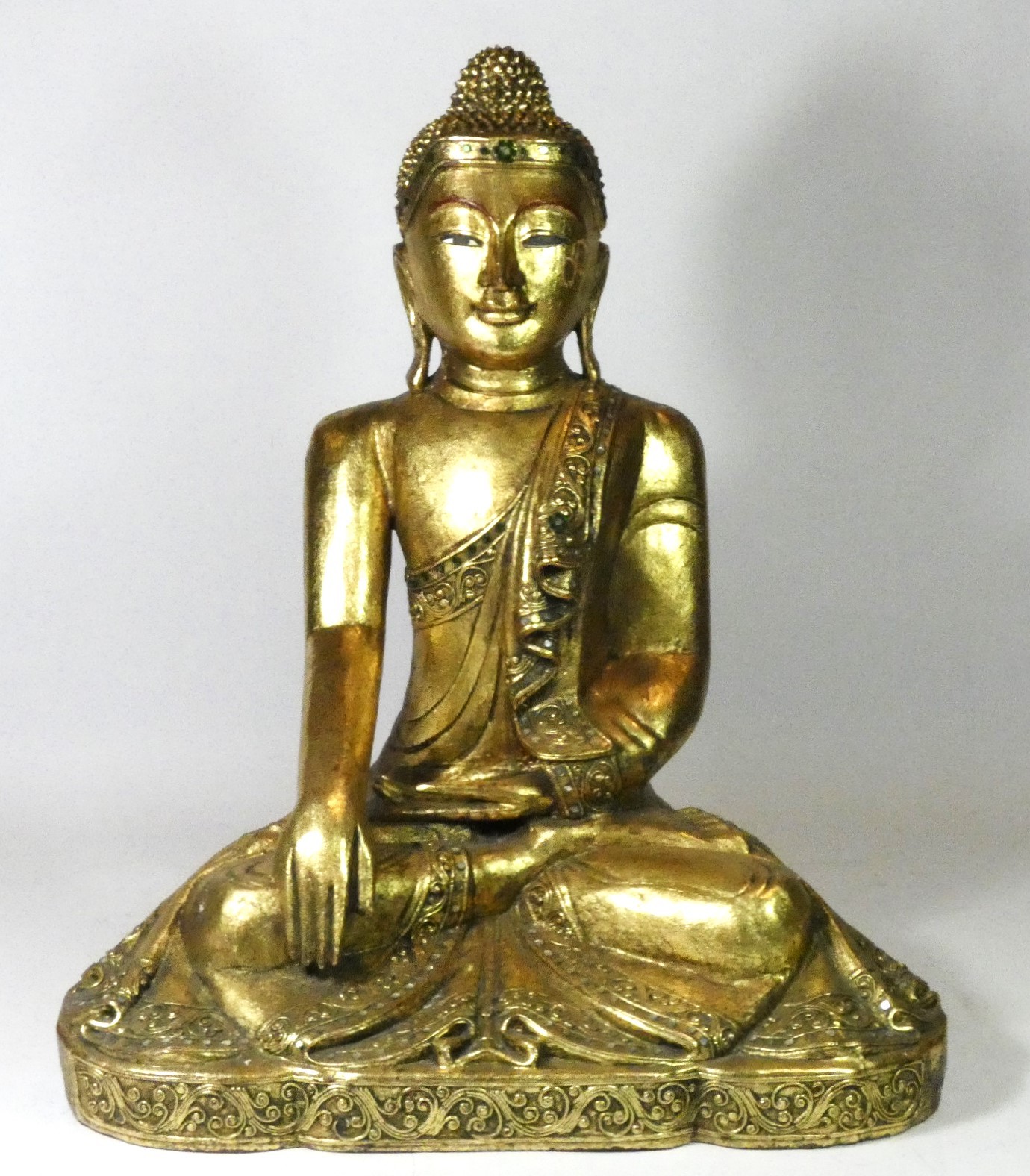 A seated carved wood Buddha, finely carved gilt scrollwork costume and headdress with inset glass