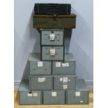 A collection of metal industrial drawers, three, two by two, one by one and two other metal boxes.