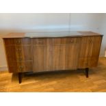 A mid 20th century teak breakfront sideboard by Validity, having central draw over twin cupboards,