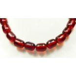 A cherry red amber bead necklace, 63gm, the largest bead 17 x 12mm