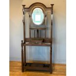 An Edwardian oak hall stand, having central swivel oval mirror, over lower draw, flanked by