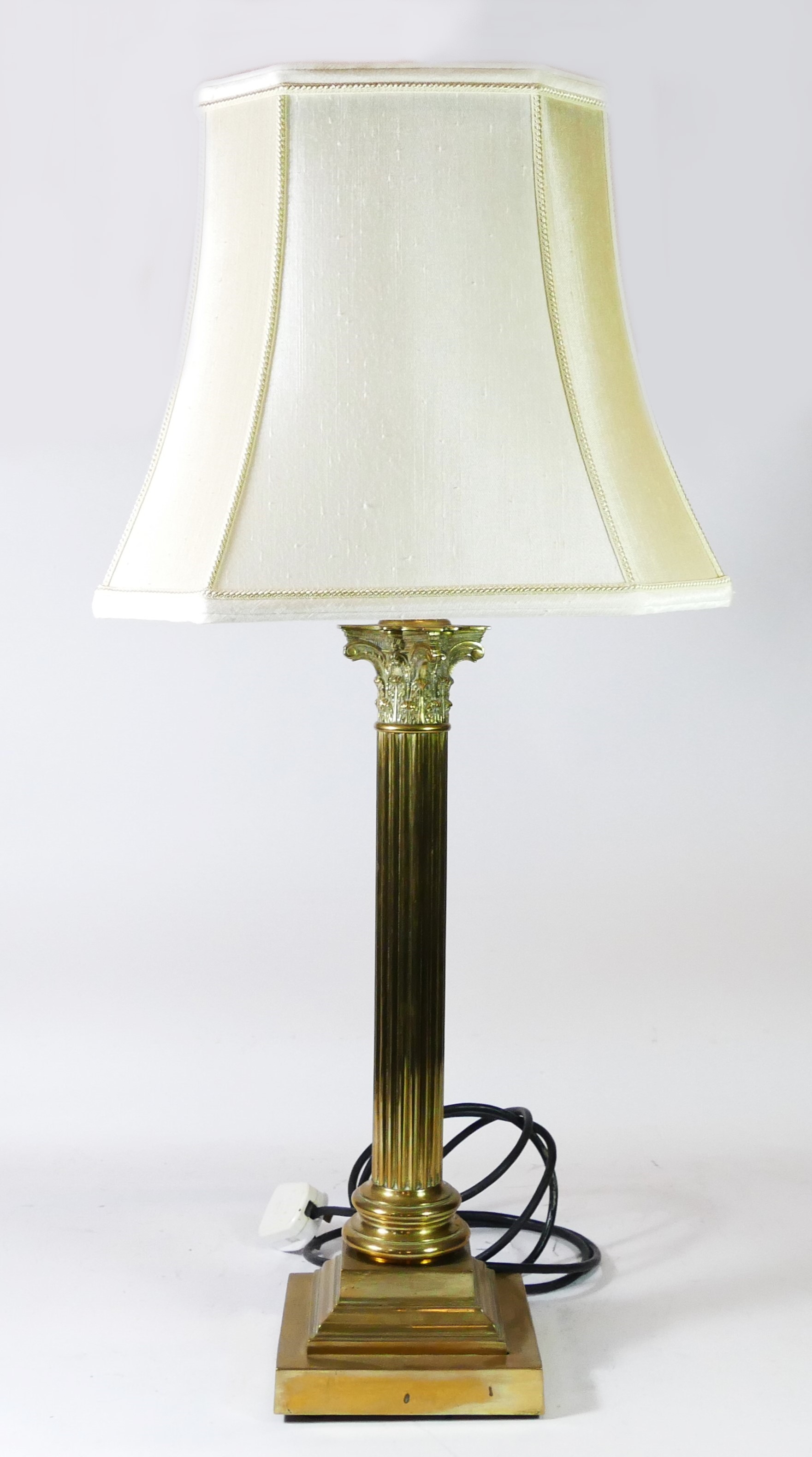 A solid brass table lamp, reeded column on a stepped base with a cream fabric shade. Overall