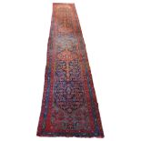 A Persian Heriz long runner, with black, dark blue and red geometric field, 109 x 580cm