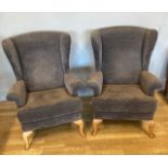 A pair of Parker knoll wingback armchairs, upholstered in plain tan fabric, raised on cabriole front