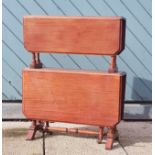 An Edwardian mahogany two tier Sutherland table, drop leaf, raised on turned supports with brass