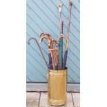 A collection of walking sticks, staffs and umbrella's, with a brass stick stand.