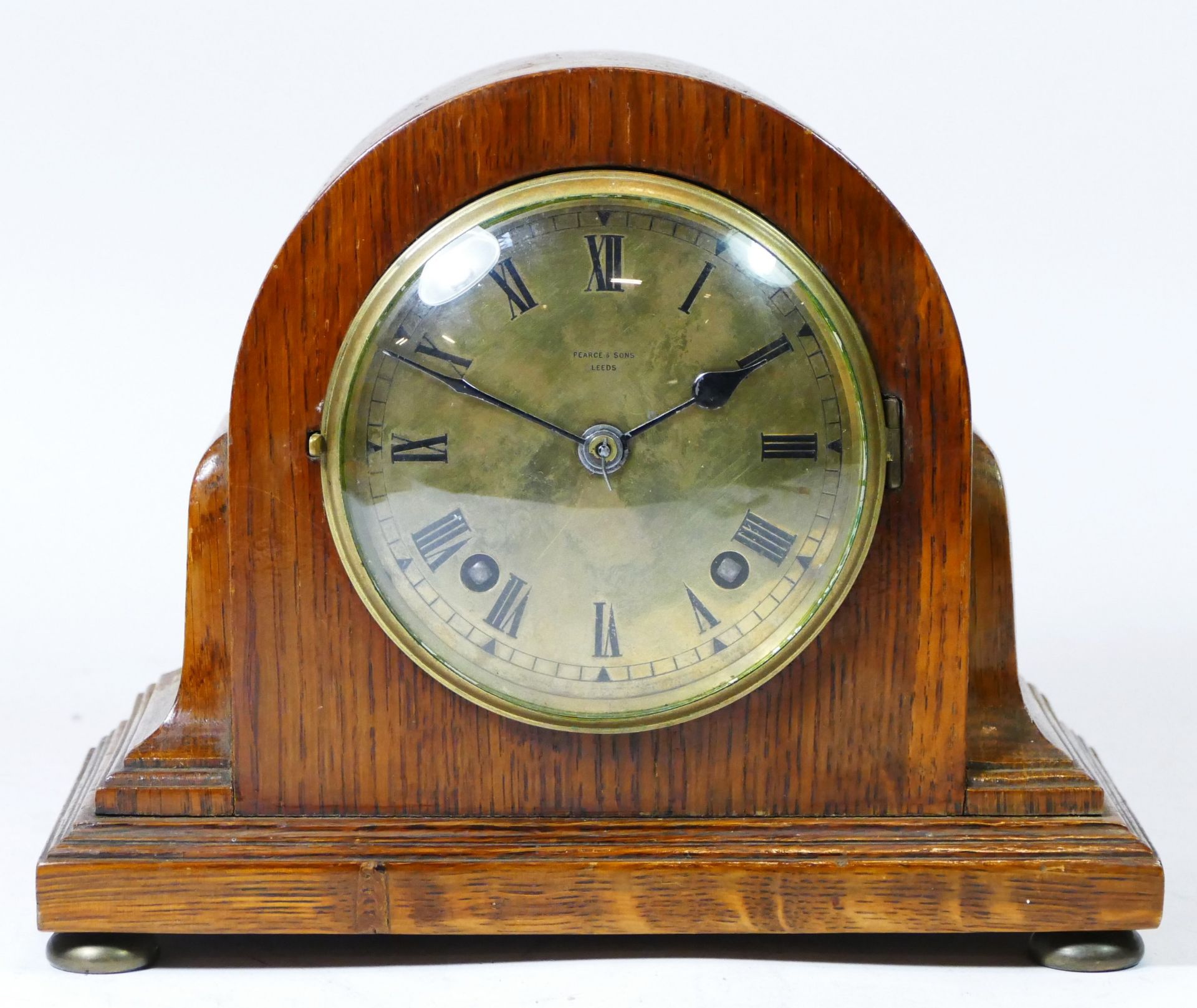 A mid 20th century oak cased mantel clock by Pearce & Sons of Leeds, having brass dial with Roman