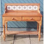 An Edwardian stripped pine washstand, having a raised tiled splashback over two frieze drawers