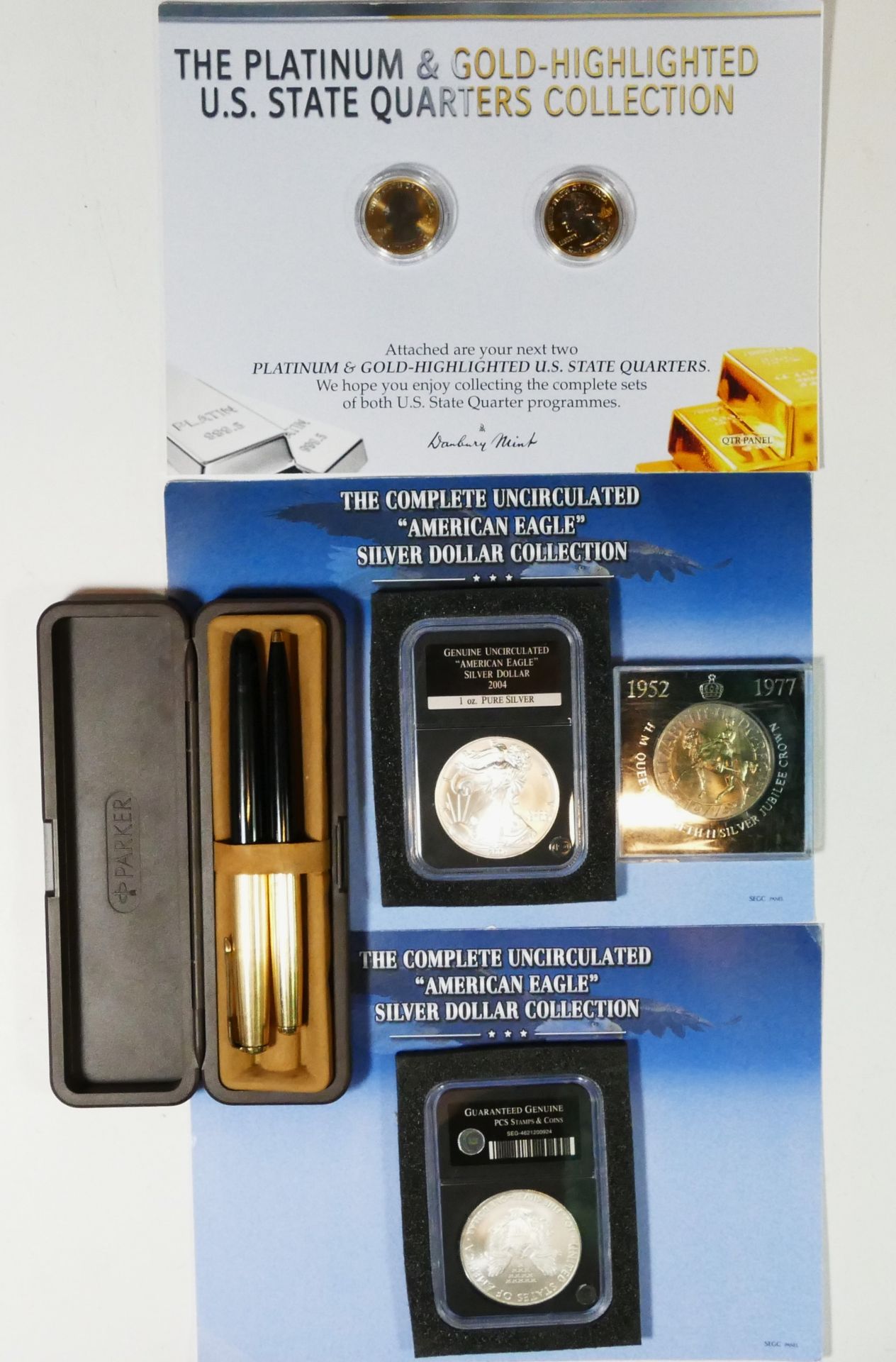 A cased Parker pen set, together with two silver dollar coins, a Silver Jubilee coin and two