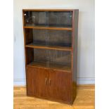 A mid 20th century teak glazed bookcase, having three height graduated shelves with sliding glass