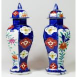 A pair of hexagonal lidded vases, hand painted in red, blue, green and white imari colours,