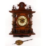 A late 19th century German wall clock, the carved mahogany case with embossed dial, enamelled