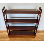 A mahogany wall shelf display unit, having scroll sides, with four shelves, over two frieze