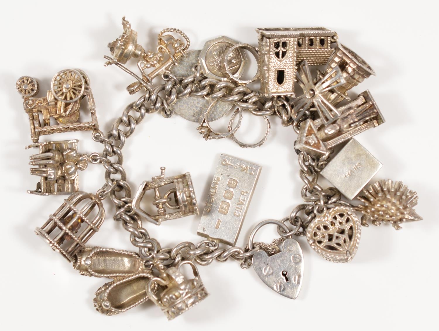 A silver charm bracelet, including a steam engine and hinged church, 103gm