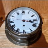 An early 20th century ships bulkhead clock, having brass case with enamelled dial and Roman