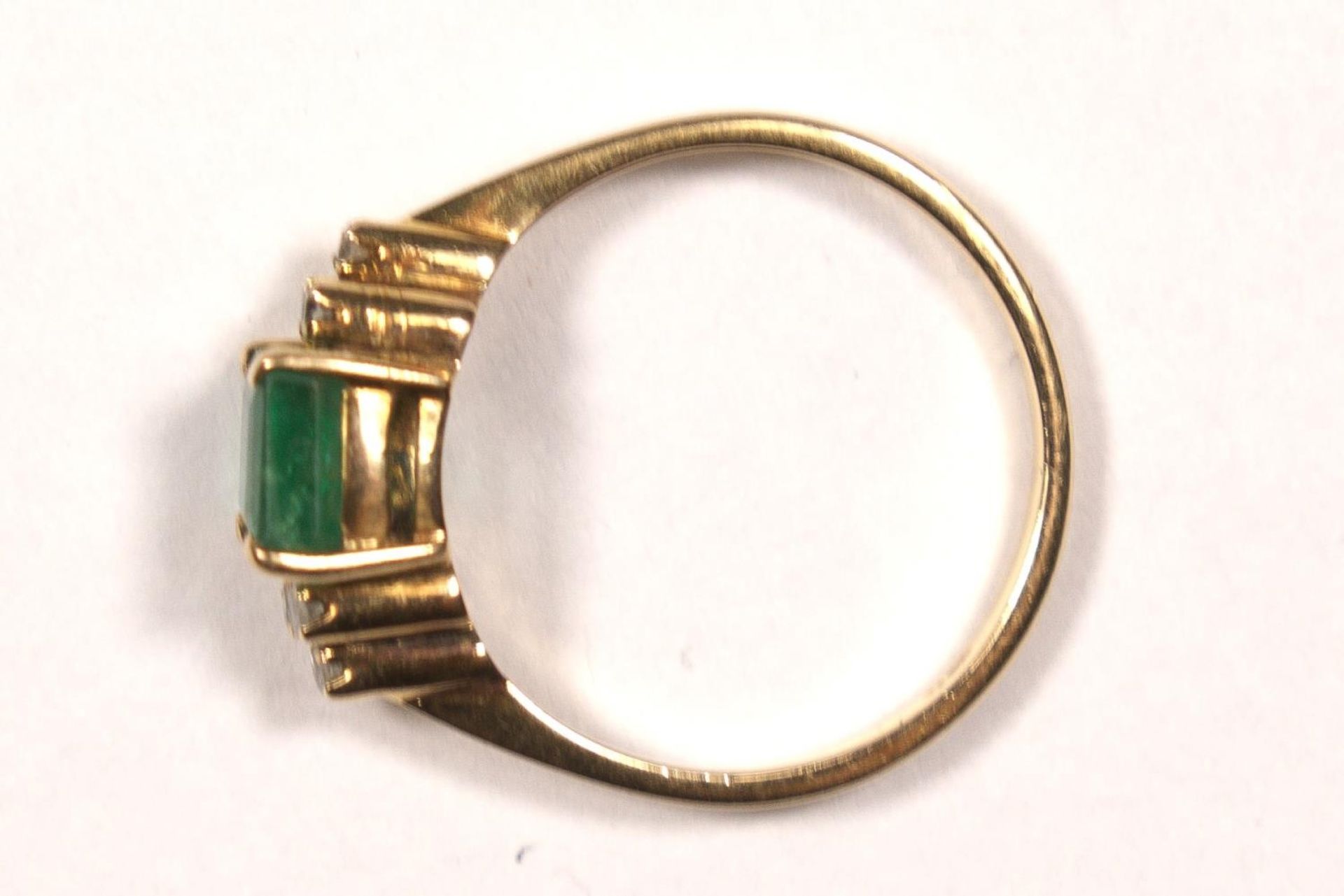 A 14K gold emerald and diamond ring, claw set with an emerald cut stone, 6 x 5mm flanked by single - Image 3 of 3