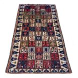 A Persian Bakhtiari woven wool rug, having burgundy and ivory ground with square floral motifs and