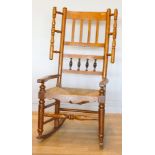 A 19th century Lancashire fruitwood winged rocking chair, having spindle back with rush seat, raised